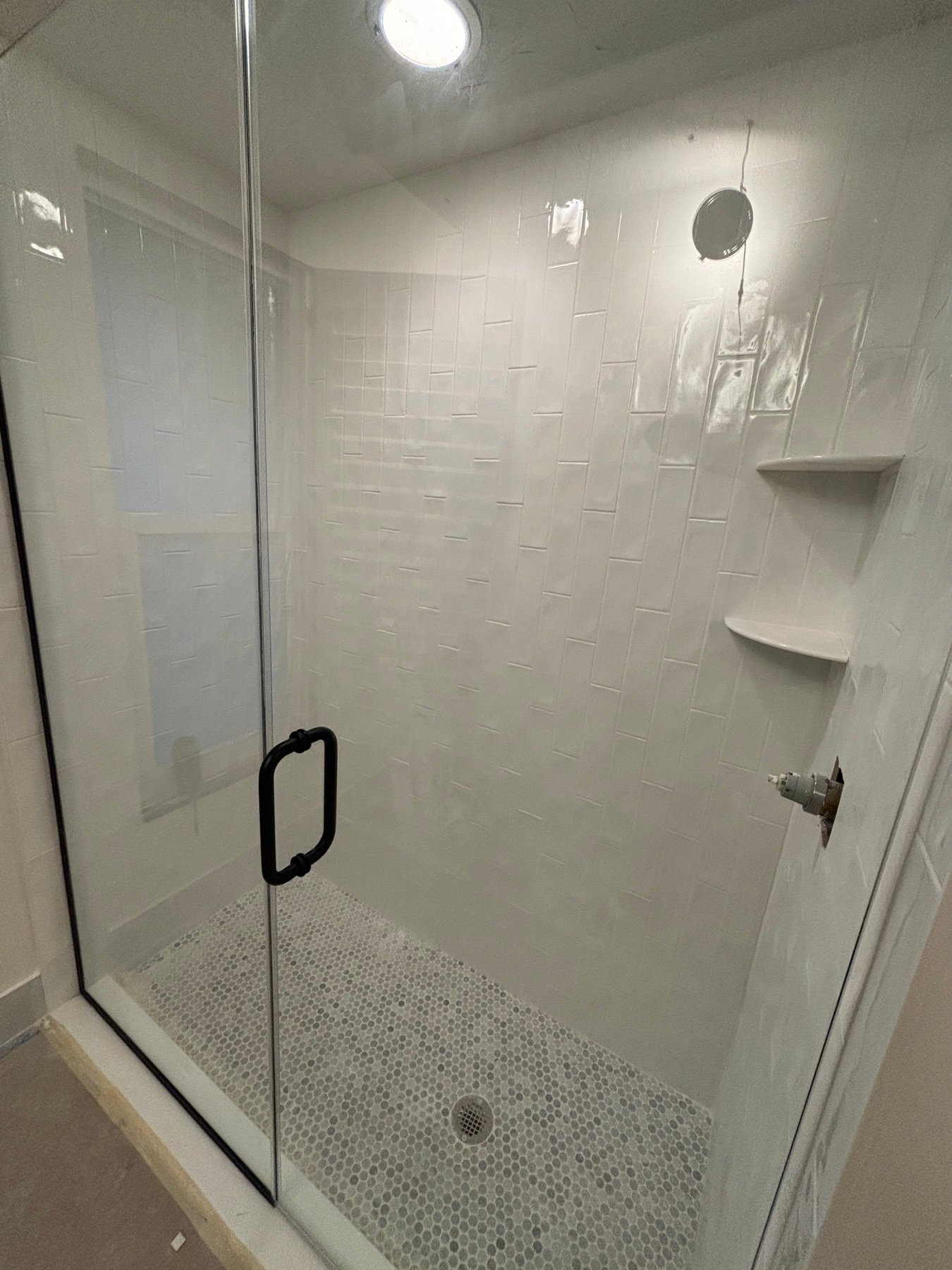 White textured shower tile with penny-round mosaic floor